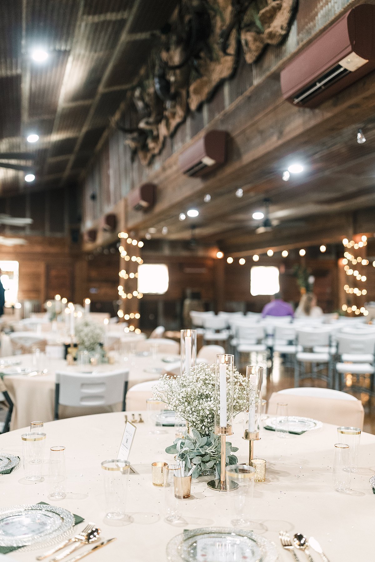 Full reception hall view with round tables string lights and elegant place settings